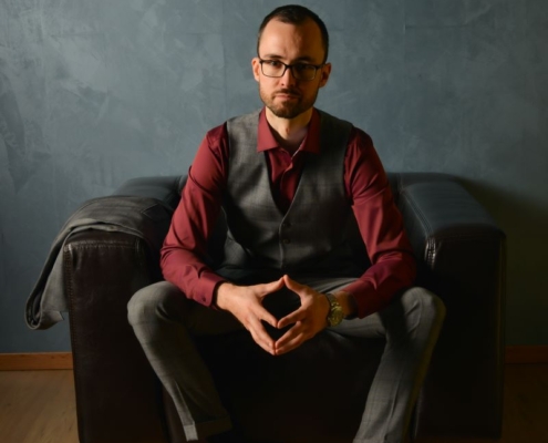 Das von Ihnen beschriebene Bild vermittelt ein lebendiges Bild von Eleganz und Selbstvertrauen. Der Mann zieht mit seinem selbstbewussten Auftreten mühelos die Aufmerksamkeit auf sich. Die Kombination aus burgunderfarbenem Hemd und grauer Weste und Hose verleiht ihm einen Hauch von Vornehmheit und ergänzt den klassischen Look seiner Brille. Seine Wahl brauner Schuhe verleiht dem Ensemble Wärme. Die strukturierte graue Wand im Hintergrund verstärkt die Gesamtästhetik, indem sie einen neutralen und dennoch stilvollen Hintergrund bietet, der seine charismatische Präsenz durchscheinen lässt.