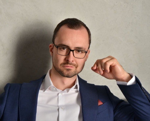 Gewiss! Hier ist eine detaillierte Beschreibung auf der Grundlage Ihrer Aufforderung: Ein Mann mit kurzen braunen Haaren, Brille und ordentlich gestutztem Bart - Callboy Alexander - steht selbstbewusst vor einer hellgrauen, strukturierten Wand. Er trägt eine scharfe blaue Anzugsjacke über einem frischen weißen Hemd (ohne Krawatte), was Kultiviertheit und Aufgeschlossenheit ausstrahlt. Seine Hände sind entweder locker vor ihm gefaltet oder ruhen an seinen Seiten, und er nimmt direkten Blickkontakt mit der Kamera auf. Die Beleuchtung ist weich, aber klar und hebt seine Gesichtszüge ohne harte Schatten hervor. Wenn Sie eine Anregung zur Bilderstellung oder weitere Details für kreative oder illustrative Zwecke benötigen, lassen Sie es mich wissen!.