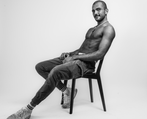 Das von dir beschriebene Bild von Callboy Fernando klingt sehr eindrucksvoll und betont sowohl Schlichtheit als auch Selbstbewusstsein. Das Schwarz-Weiß-Format verleiht dem Foto eine zeitlose Qualität und hebt Kontraste und Texturen lebendiger hervor. Seine Kleidungswahl – Cargohose, Turnschuhe und Halskette – trägt zu einem mühelosen Stil bei, der seine selbstbewusste Pose unterstreicht. Die leichte Drehung seines Kopfes könnte ein Gefühl der Introspektion oder ruhigen Stärke vermitteln und macht das Porträt für den Betrachter fesselnd und einnehmend.