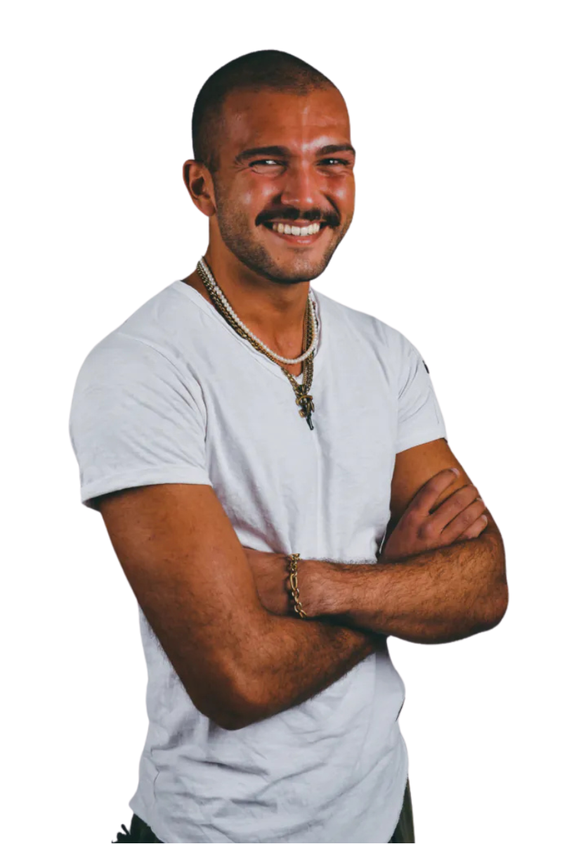 Dieses Bild von Callboy Karim zeigt eine markante und selbstbewusste Pose. Der rasierte Kopf und der Schnurrbart verleihen ihm ein unverwechselbares Aussehen, während sein Lächeln Wärme und Nähe vermittelt. Das weiße T-Shirt kontrastiert mit dem schlichten weißen Hintergrund, lässt ihn hervorstechen und verleiht dem Bild eine klare und minimalistische Ästhetik. Die verschiedenen Halsketten verleihen seinem Erscheinungsbild Persönlichkeit und Stil und deuten auf ein Interesse an Mode und persönlichem Ausdruck hin. Seine verschränkten Arme unterstreichen sein selbstbewusstes Auftreten und vermitteln Vertrauen in sich selbst und in das, was er repräsentiert oder fördert.