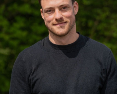 Es klingt, als würden Sie ein Porträtfoto von jemandem namens Callboy Vito beschreiben. Auf diesem Bild hat er: – kurze braune Haare – einen ordentlich gestutzten Bart – ein sanftes Lächeln – steht im Freien – trägt ein schlichtes schwarzes Sweatshirt – der Hintergrund besteht aus verschwommenem grünem Laub, das an die Natur oder eine Parkkulisse erinnert. Wenn Sie Fragen zu dieser Beschreibung haben oder Hilfe bei der Verfeinerung benötigen (z. B. beim Schreiben, bei Kunstreferenzen, bei Bildunterschriften), lassen Sie es mich wissen!.