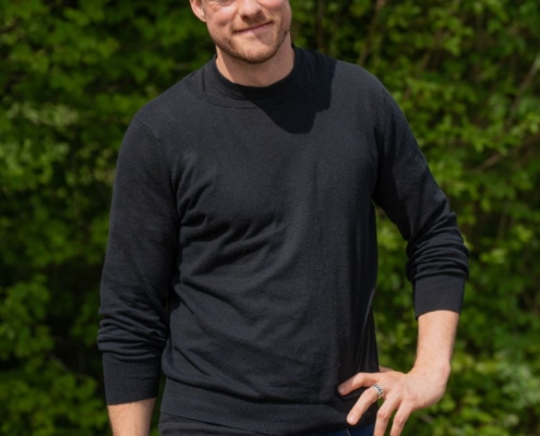 Verstanden! Sie beschreiben einen Mann, der im Freien steht, umgeben von üppigem Grün. Er hat kurzes braunes Haar und trägt ein schwarzes Langarmshirt und Bluejeans. Seine Haltung ist lässig – eine Hand auf der Hüfte, die andere entspannt, sein Gesichtsausdruck ein leichtes Lächeln, das lässiges Selbstbewusstsein ausstrahlt. Pose und Ausstrahlung erinnern an „Callboy Vito“ und suggerieren einen entspannten Charme und eine offene Art. Wenn Sie ein Bild oder Porträt anhand dieser Beschreibung erstellen lassen möchten, finden Sie hier einen Vorschlag für einen Künstler oder einen KI-Bildgenerator: „Ein Mann mit kurzem braunem Haar steht im Freien vor dichtem Grün. Er trägt ein schwarzes Langarmshirt und Bluejeans. Eine Hand ruht auf der Hüfte, während er leicht lächelt und so eine lässige Ausstrahlung ausstrahlt, die an Callboy Vito erinnert.“ Lassen Sie mich wissen, wenn Sie Hilfe bei der weiteren Anpassung der Beschreibung benötigen!.