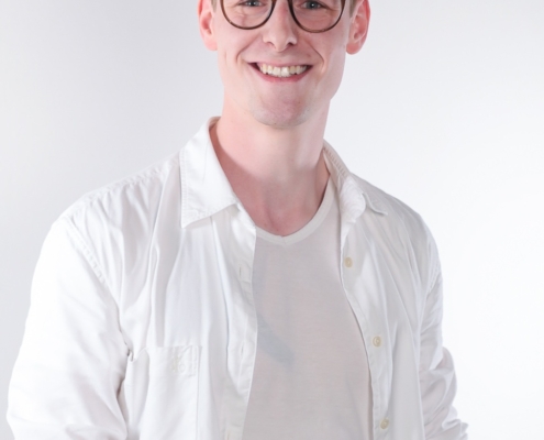 Es klingt, als würdest du das Bild eines jungen Mannes namens Callboy Karim beschreiben, der kurze, zerzauste Haare und eine Brille hat. Er trägt ein weißes Hemd über einem weißen T-Shirt und steht vor einem schlichten weißen Hintergrund, während er in die Kamera lächelt. Wenn du Hilfe bei der Verfeinerung dieser Beschreibung für kreatives Schreiben, Social-Media-Untertitel oder andere Zwecke benötigst, lass mich gerne wissen, wie du sie verwenden möchtest!.
