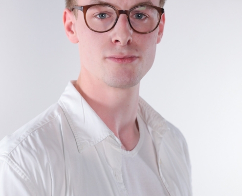 Natürlich! Hier ist eine detaillierte Beschreibung Ihrer Figur, Callboy Karim, geeignet als Referenz oder für textbasierte Szenarien: --- Callboy Karim steht vor einem schlichten, hellen Hintergrund. Er ist ein junger Mann mit kurzen, unordentlichen braunen Haaren, die ihm in losen Strähnen in die Stirn fallen. Seine Brille umrahmt seinen aufmerksamen Blick und verleiht ihm ein intelligentes und zugängliches Aussehen. Er trägt ein frisches weißes Hemd, das oben aufgeknöpft ist und darunter ein lässiges weißes T-Shirt freigibt. Die Lagen unterstreichen seinen entspannten und dennoch gepflegten Look. Karims Haltung ist ruhig und selbstbestimmt; er blickt mit stiller Zuversicht direkt in die Kamera, die Lippen neutral, weder lächelnd noch stirnrunzelnd – einfach gelassen. Die Gesamtkomposition ist schlicht und minimalistisch: nur Karim vor einem weichen, hellen Hintergrund, der sein nachdenkliches Auftreten und seinen zurückhaltenden Stil unterstreicht. ---.