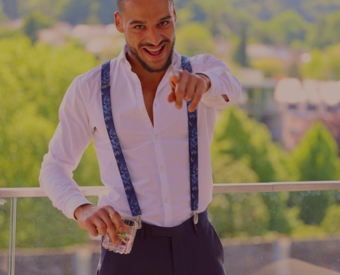 Es klingt, als würden Sie das Bild eines Mannes namens "Callboy Steve" beschreiben, der mit einem weißen Hemd, blauen Hosenträgern und einer dunklen Hose gut gekleidet ist. Er steht auf einem Balkon, lächelt selbstbewusst und deutet in die Kamera, während er einen Stapel Bargeld in der Hand hält. Der Hintergrund ist unscharf, zeigt aber grüne Bäume und einige Gebäude. Wenn Sie Hilfe beim Schreiben einer Bildunterschrift oder eines Alt-Textes für die Barrierefreiheit benötigen, finden Sie hier ein Beispiel: Alt-Text: Ein Mann, bekannt als Callboy Steve, steht auf einem Balkon und trägt ein weißes Hemd, blaue Hosenträger und eine dunkle Hose. Er lächelt breit, während er mit einer Hand in die Kamera zeigt und in der anderen einen aufgefächerten Stapel Bargeld hält. Im unscharfen Hintergrund sind grüne Bäume und mehrere Gebäude zu sehen. Lassen Sie mich wissen, wenn Sie diese Beschreibung verfeinern möchten oder sie für einen anderen Zweck benötigen!.