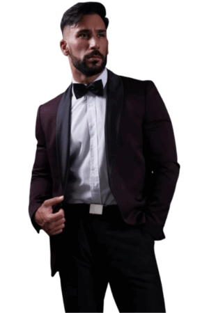 Bärtiger Mann im dunklen Smoking, weißem Hemd, schwarzer Fliege und Hose, Hand in der Tasche, posiert vor weißem Hintergrund mit elegantem Callboy Amador-Flair.