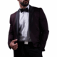 Bärtiger Mann im dunklen Smoking, weißem Hemd, schwarzer Fliege und Hose, Hand in der Tasche, posiert vor weißem Hintergrund mit elegantem Callboy Amador-Flair.