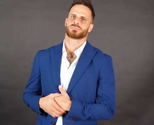 Es klingt, als würden Sie ein bestimmtes Bild von Callboy Vito beschreiben. Da Ihre Aufforderung detailliert und visuell ist, hier eine mögliche kurze Beschreibung als Referenz oder als Plattform: Ein Mann mit kurzen Haaren und einem Bart - bekannt als Callboy Vito - steht vor einem schlichten dunklen Hintergrund. Er trägt einen blauen Anzug mit einem weißen Hemd, die Hände vor sich verschränkt. Er blickt leicht nach oben und hat einen neutralen Blick. Wenn Sie ein KI-Bild erstellen möchten oder Vorschläge zur weiteren Verfeinerung der Beschreibung benötigen (z. B. Details zur Pose, Beleuchtung oder zum emotionalen Ton), lassen Sie es mich wissen!.