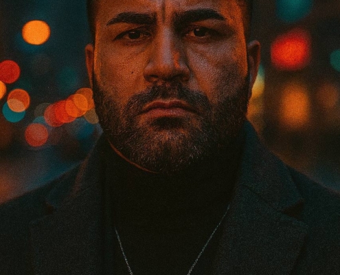 Ein Mann mit ernster Miene und einem Vollbart steht nachts im Freien. Er trägt einen dunklen Mantel und eine Halskette, die an den Stil des Callboy Dahro erinnern. Die Szene wird von bunten, verschwommenen Stadtlichtern im Hintergrund eingerahmt, die einen lebhaften Kontrast zu seiner düsteren Stimmung bilden.