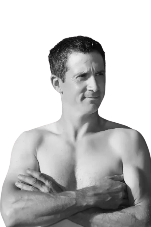 Callboy Fabian, ohne Hemd und mit kurzen dunklen Haaren, steht mit verschränkten Armen auf einem Schwarz-Weiß-Foto vor einem schlichten weißen Hintergrund.