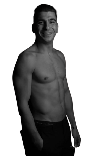 Callboy Mike, ein grinsender, hemdsärmeliger junger Mann in dunklen Shorts, steht teilweise zur Seite gedreht; schwarz-weißer, schlichter Hintergrund.